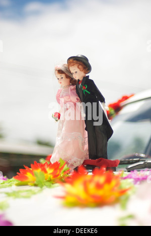 Miniature smart couple based on front car ready for wedding with flowers on their feet Stock Photo
