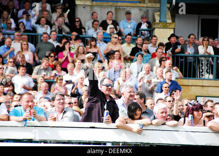 Crowd of people watching, drinking and some people winning during horse racing Stock Photo