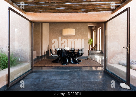 Glass patio doors opening to table and chairs in gloss black. Interior design and decoration Romain Michel-Meniere Stock Photo