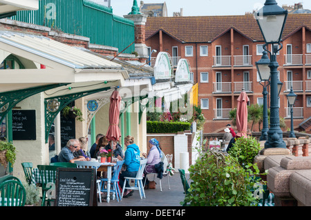 People eating outside cafes and restaurants along West Cliff Arcade overlooking the harbour at Ramsgate. Stock Photo