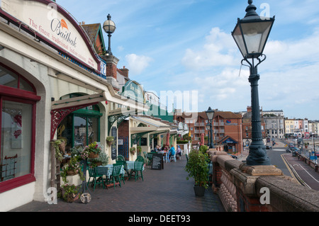 People eating outside cafes and restaurants along West Cliff Arcade overlooking the harbour at Ramsgate. Stock Photo