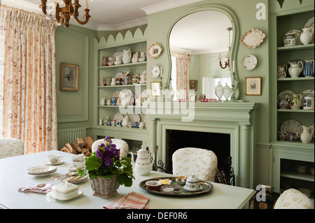 Country house dining room with pottert collection on recessed shelving painted in pastel green Stock Photo