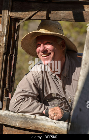 Smiling man looking through the window of an old cabin along the Salmon River in Idaho. Stock Photo