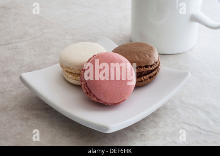 Strawberry/Raspberry, vanilla and chocolate flavoured French-style macaroons on a square plate with a mug; Stock Photo