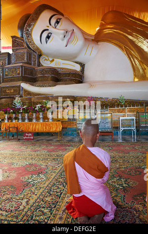 Nun in front of reclining Buddha statue, Shwethalyaung, Bago (Pegu), Myanmar (Burma), Asia Stock Photo