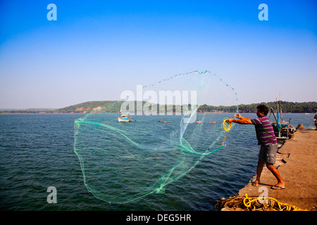 Fisherman throwing a fishing net in the sea, Chapora Harbour, Chapora, Bardez, North Goa, Goa, India Stock Photo