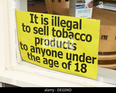 it is illegal to sell tobacco sign Illegal to sell tobacco under 18 sign in shop window uk Stock Photo