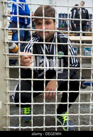 Diego Ribas da Cunha of VfL Wolfsburg paints the fence of the TSG Calbe Heger stadium in Calbe, Germany, 18 September 2013. Three months after floodwaters damaged the stadium VfL Wolfsburg helps the club from Calbe. Photo: PETER ENDING Stock Photo