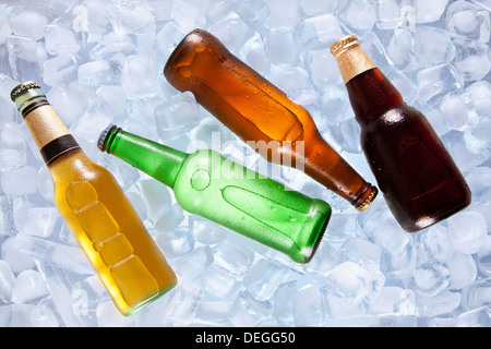 Four different bottles of beer cooling on ice. Stock Photo