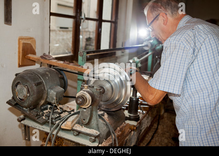 Old senior craftsman working on the lathe in his workshop in Brianza near Milan, Italy Stock Photo