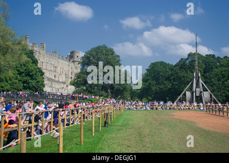 Crowds gather to watch the Jousting Tournament with the Wooden Trebuchet in the background at Warwick Castle, England, UK Stock Photo