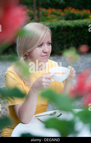Young woman drinking tea in a white cup outdoors Stock Photo