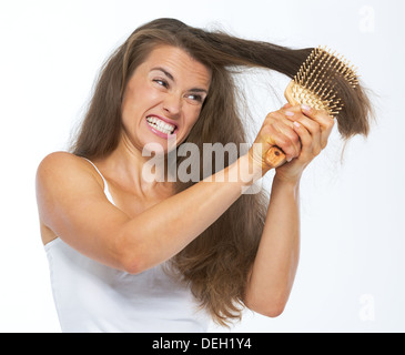 Angry woman having hard time combing hair Stock Photo