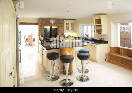 A bespoke country kitchen in a house in the UK using the trunk of a tree as a breakfast island. Stock Photo