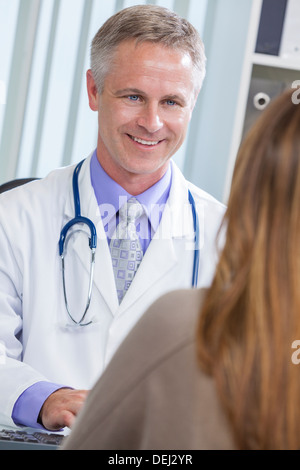 Male medical doctor or general practitioner talking to a female patient in a hospital office Stock Photo