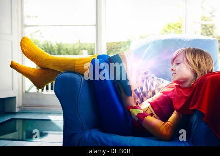 Little boy dressed as a super hero reading a book Stock Photo