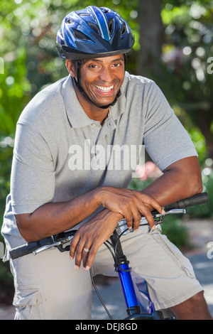 An African American man riding bicycle in the summer smiling and happy Stock Photo