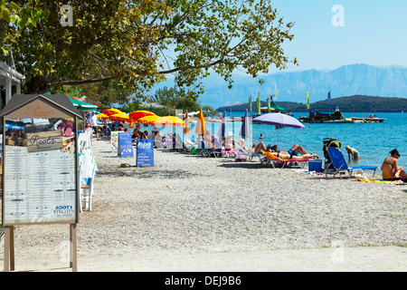 Taverna menu on beach front in Nidri Lefkas Lefkada Greek Island Greece Restaurant on coast sunbathers sunbathing Nydri Stock Photo