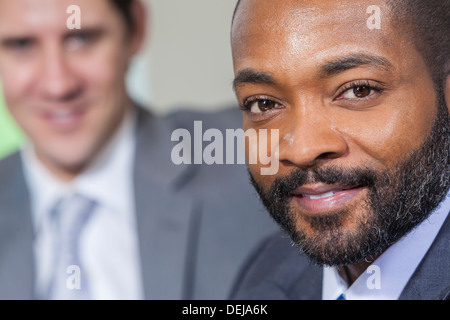 Successful African American businessman or man with his Caucasian colleague behind him Stock Photo