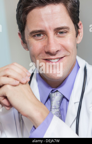 A male doctor in a white coat, wearing a shirt, tie and stethoscope Stock Photo