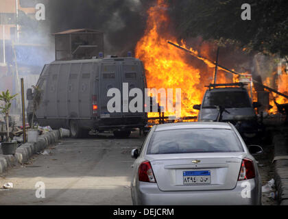 Cairo, Cairo, Egypt. 19th Sep, 2013. Egyptians walk past a burning police car in front of al-Zamalek football club's headquarters in Cairo on Sept. 19, 2013. Members of a hardcore group of fans of the Zamalek football club, the Ultra White Knights (UWK), stormed the club's headquarters in Cairo on Thursday following a protest demanding changes to the club's leadership Credit:  Ahmed Asad/APA Images/ZUMAPRESS.com/Alamy Live News Stock Photo