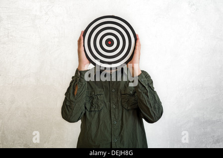 Man holding dartboard in place of head. Stock Photo