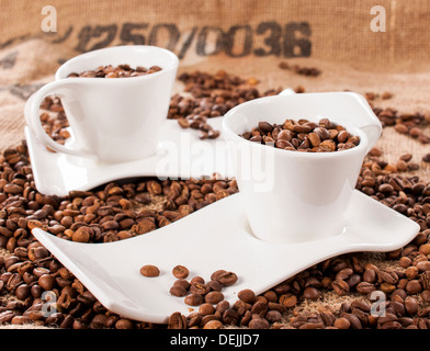 Large group of the coffee beans spashed and in cups. selective focus on the front cup Stock Photo
