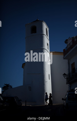 A couple walk in front of the Torre del Reloj (clock tower) in Zahara de la Sierra, Cadiz, Andalusia, Spain, June 13, 2013. Stock Photo