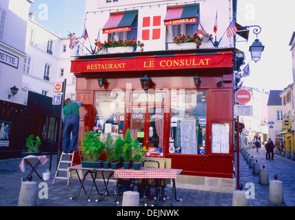 View of a man painting 'Le Consulat' restaurant on top of Montmarte in the 18th  arrondissement of Paris France Stock Photo