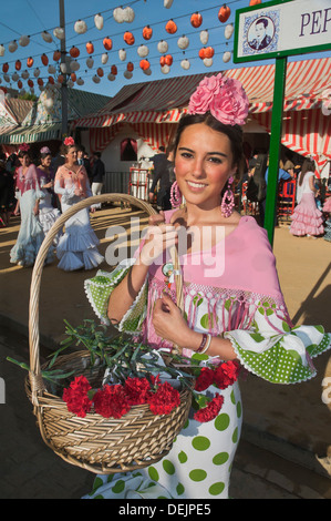 April Fair, Young woman wearing a traditional flamenco dress and with flower basket, Seville, Region of Andalusia, Spain, Europe Stock Photo