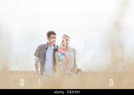 Thoughtful young couple looking away while standing field Stock Photo