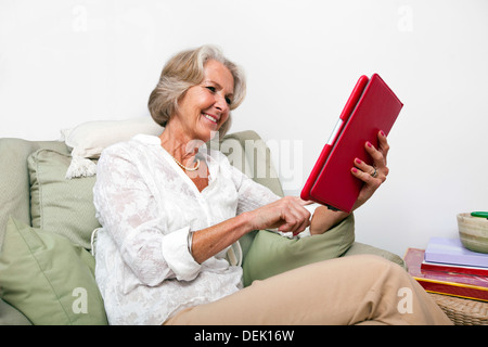 Senior woman using digital tablet on armchair home Stock Photo