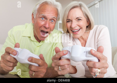 Senior couple, man and woman, laughing & having fun playing video console games together. Stock Photo