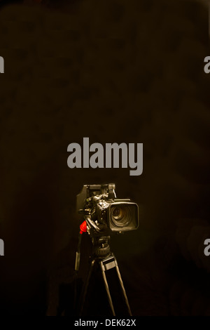 Digital camera and tripod against black background Stock Photo - Alamy