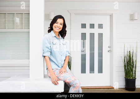 Hispanic woman smiling on front porch Stock Photo