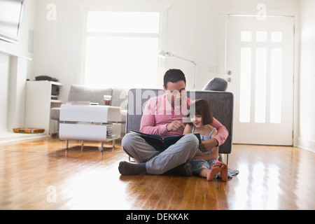 Father and daughter using digital tablet in living room Stock Photo