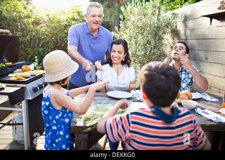 Family eating at table outdoors Stock Photo