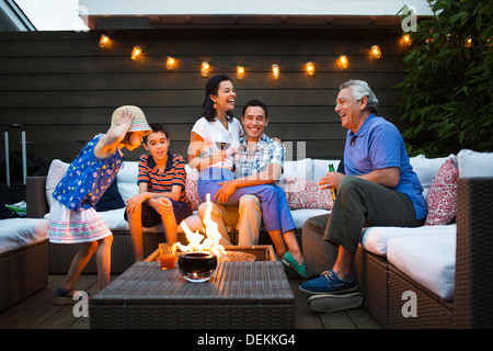 Family relaxing around fire pit outdoors Stock Photo
