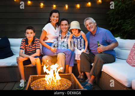 Family smiling around fire pit outdoors Stock Photo