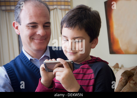 Hispanic father and son using cell phone Stock Photo