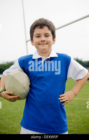 Hispanic boy holding rugby ball on field Stock Photo