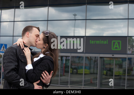 Two people in the airport kissing in fron of arrival gate Stock Photo