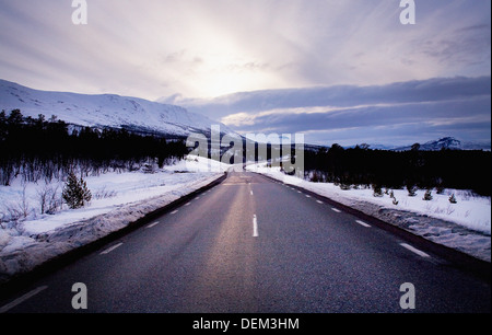 Road at Sunset in Winter with Mountains in Background Stock Photo