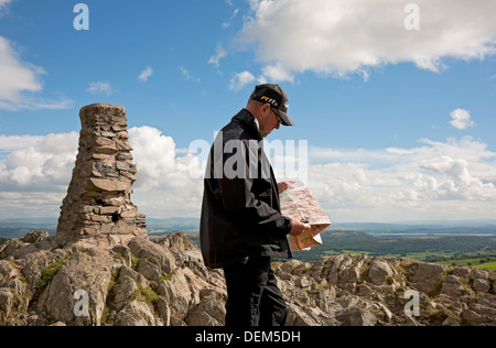 Man walker tourist holding compass and reading map of the Lake District National Park in summer Gummers How Cumbria England UK United Kingdom Britain Stock Photo