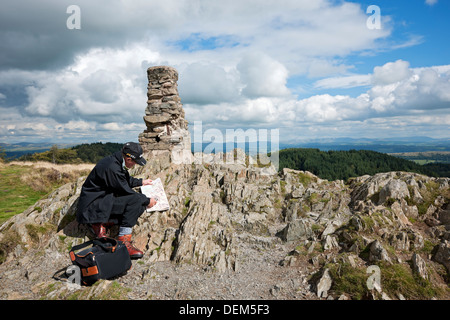 Man walker tourist holding compass and reading map of the Lake District in summer Gummers How Cumbria England UK United Kingdom GB Great Britain Stock Photo