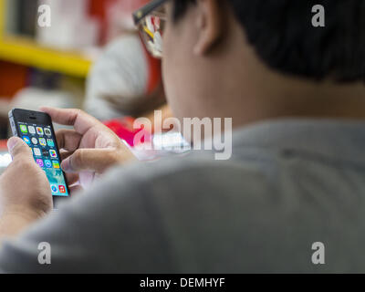 Bangkok, Thailand. 21st Sep, 2013. A man looks at the screen of an iPhone 5s before buying the phone at an electronics shop in MBK in Bangkok. Customers around the world lined up Friday to pick up Apple's new flagship iPhone 5s and its lower cost, more colorful brother, the iPhone 5c. The phones went on sale in the US and select countries beyond the US on Friday. The iPhone 5s and iPhone 5c will not be officially released in Thailand until late 2013 but the phones are available through the unofficial grey market in MBK, a huge shopping complex in Bangkok with dozens of small electronics shop Stock Photo