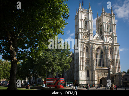 The tall western facade of London's Westminster Abbey with a new generation red London Routemaster double-decker bus passing-by. Stock Photo