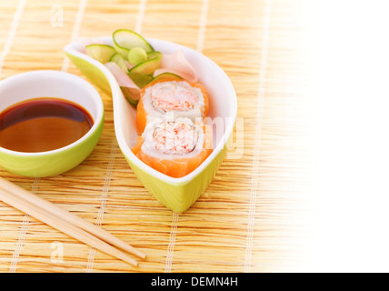 Sushi served with wooden chopsticks and soy sauce on bamboo tablecloth, asian food, california roll, tasty meal, exotic delicacy Stock Photo