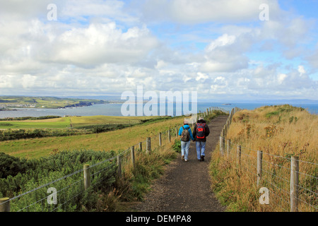 Couple walking along footpath above the Giants Causeway, Northern Ireland. Stock Photo
