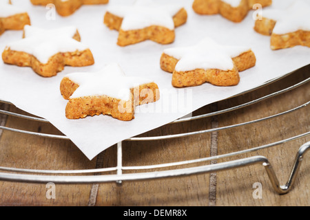 cinnamon stars on a parchment paper on a cooling grid with wooden background Stock Photo